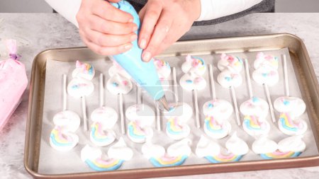 Téléchargez les photos : Pas à pas. Piping meringue mélanger en pops en forme de licorne sur une plaque de cuisson doublée de papier parchemin. - en image libre de droit