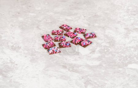 Photo for Gourmet dark mini chocolates with drizzled pink chocolate and fancy sprinkles on top. - Royalty Free Image