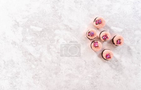 Téléchargez les photos : Flat lay. Freshly baked chocolate strawberry cupcakes garnished with gourmet mini pink chocolates. - en image libre de droit