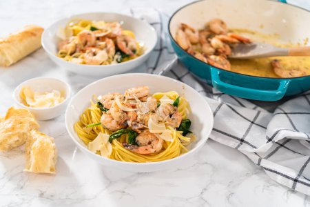 Photo for Serving garlic shrimp pasta with spinach in white ceramic bowls. - Royalty Free Image
