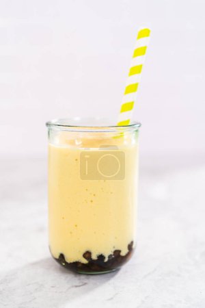 Téléchargez les photos : Smoothie de mangue boba fraîchement préparé dans un verre à boire avec une paille de papier. - en image libre de droit