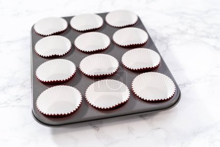 Foto de Forro de molde para cupcakes con papel de aluminio para hornear cupcakes de terciopelo rojo con glaseado de ganache de chocolate blanco. - Imagen libre de derechos