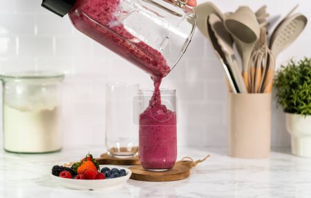 Photo for Pouring freshly made mixed berry smoothie into a drinking glass. - Royalty Free Image