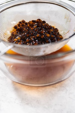 Foto de Escurrir perlas de boba recién cocidas a través de un colador de malla. - Imagen libre de derechos