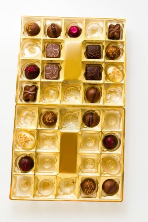 Téléchargez les photos : Chocolats gourmands en boîte dorée sur fond blanc
. - en image libre de droit