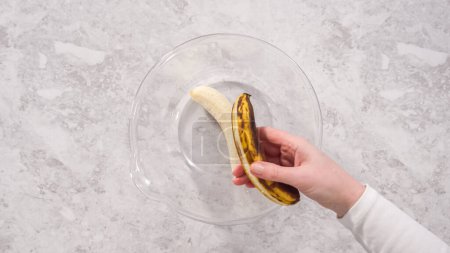 Photo for Flat lay. Step by step. Smashing riped bananas in a glass mixing bowl to prepare coconut banana pancakes. - Royalty Free Image