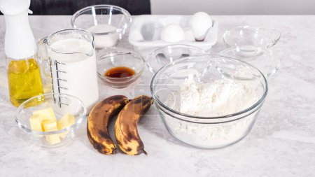 Foto de Paso a paso. Ingredientes medidos en cuencos de vidrio para preparar panqueques de plátano de coco para el desayuno. - Imagen libre de derechos