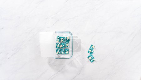 Photo for Flat lay. Packaging mini mermaid chocolate bars into a food glass container for storage. - Royalty Free Image