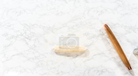 Foto de Acostado. Rolling bread tough con un rodillo francés para hornear pasteles de canela sin levadura. - Imagen libre de derechos