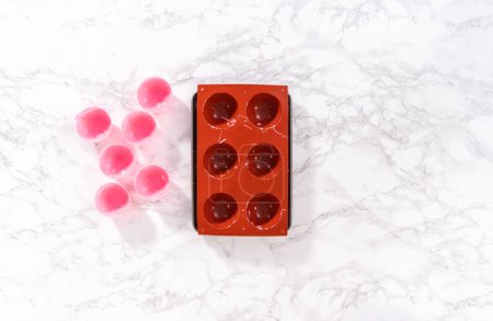 Foto de Quitar las cáscaras de chocolate rosa de los moldes de chocolate de silicona con chocolate rosa derretido para preparar bombas de chocolate caliente. - Imagen libre de derechos