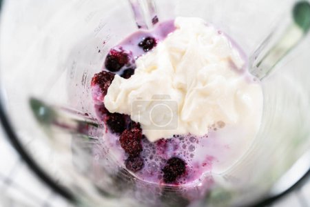 Foto de Mixing ingredients in kitchen blender to prepare mixed berry boba smoothie. - Imagen libre de derechos