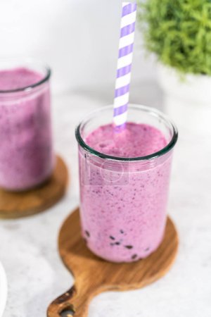 Téléchargez les photos : Freshly made mixed berry boba smoothie in a drinking jar with paper straw. - en image libre de droit
