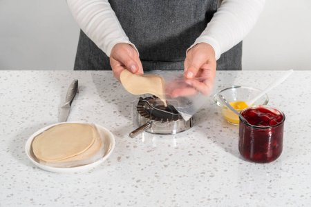 Téléchargez les photos : Remplissage de pâte empanada avec garniture tarte cerise pour faire des empanadas cerise douce dans la friteuse à air. - en image libre de droit