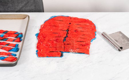 Foto de Rolling masa de pan rojo y azul para hornear giros patrióticos de canela. - Imagen libre de derechos