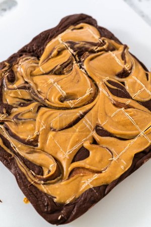 Photo for Scoring chocolate fudge with peanut butter swirl for cutting into small pieces. - Royalty Free Image