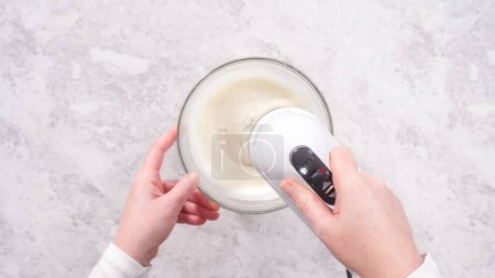 Foto de Acostado. Paso a paso. Mezclar los ingredientes en un tazón de vidrio para preparar glaseado de queso crema. - Imagen libre de derechos