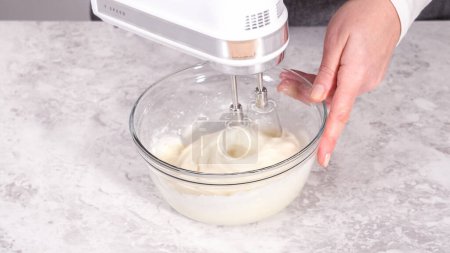 Photo for Step by step. Mixing ingredients in a glass mixing bowl to prepare cream cheese frosting. - Royalty Free Image