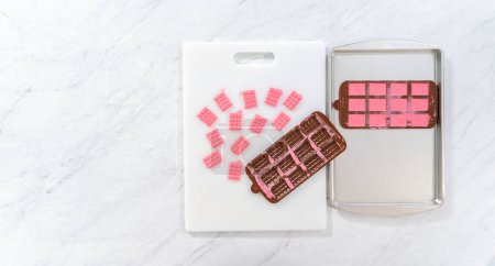 Photo for Flat lay. Removing mini pink chocolates from silicone chocolate mold. - Royalty Free Image