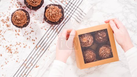 Photo for Flat lay. Step by step. Packaging chocolate cupcakes with chocolate ganache frosting into a paper cupcake box. - Royalty Free Image
