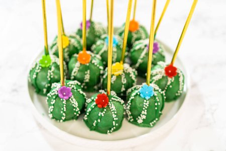 Téléchargez les photos : Gâteaux éclatants en forme de cactus, joliment décorés avec de la poussière de lustre, des fleurs de sucre et des paillettes blanches, arrangés pour célébrer Cinco de Mayo. - en image libre de droit