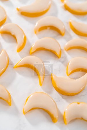 Téléchargez les photos : Biscuits au citron avec glaçage au citron. Tremper les biscuits au citron dans un glaçage au citron. - en image libre de droit