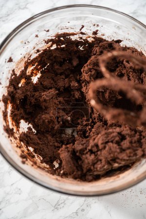 Foto de Mezclar ingredientes en un tazón de vidrio grande para hornear galletas de chocolate blanco de menta. - Imagen libre de derechos