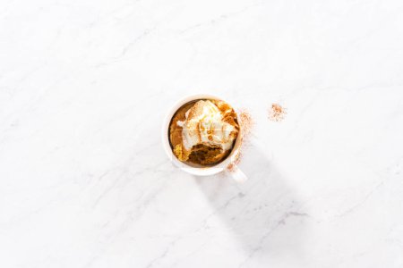 Photo for Flat lay. Pumpkin mug cake garnished with homemade whipped cream and cinnamon. - Royalty Free Image
