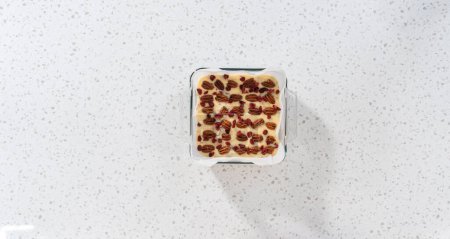 Foto de Acostado. Corte de chocolate blanco dulce de nuez de arándano en trozos pequeños en una tabla de cortar blanca. - Imagen libre de derechos