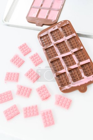 Photo for Removing mini pink chocolates from silicone chocolate mold. - Royalty Free Image