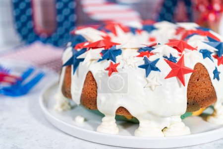 Foto de Tarta de 4 de julio cubierta con un esmalte de vainilla y decorada con estrellas de chocolate en un plato blanco. - Imagen libre de derechos