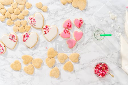 Téléchargez les photos : Pose plate. Décoration de biscuits au sucre en forme de cœur avec glaçage royal rose et blanc pour la Saint-Valentin. - en image libre de droit