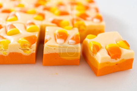 Téléchargez les photos : Bonbons faits maison morceaux carrés de caramel de maïs sur une planche à découper blanche. - en image libre de droit