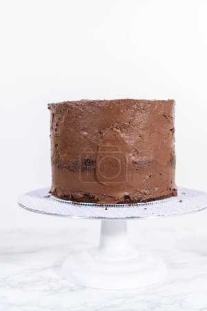 Photo for Covering chocolate cake with a crumb layer of chocolate buttercream frosting. - Royalty Free Image