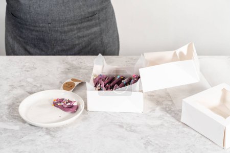 Téléchargez les photos : Packaging homemade mermaid pretzel twists into a white paper box. - en image libre de droit