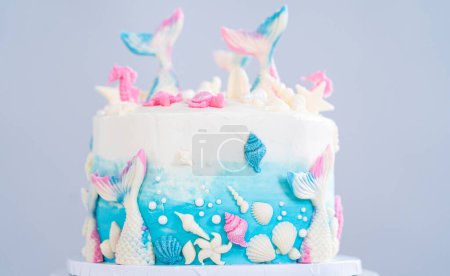 Foto de Pastel de vainilla de 3 capas con temática sirena decorado con colas de sirena de chocolate y conchas marinas en un soporte de pastel blanco. - Imagen libre de derechos