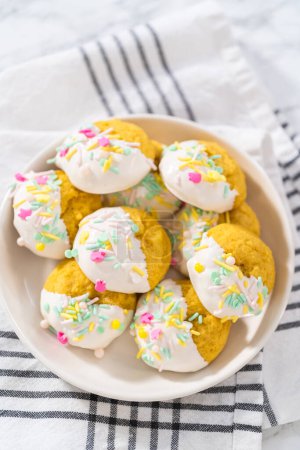 Photo for Lemon Cookies with White Chocolate. Freshly baked lemon cookies with white chocolate and decorated with Easter sprinkles on a white ceramic plate. - Royalty Free Image
