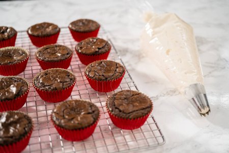 Foto de Piping peppermint buttercream glaseado en la parte superior de los cupcakes de chocolate y la decoración con caramelos de caña de menta picada. - Imagen libre de derechos