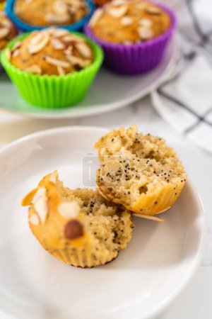Foto de Magdalenas de semilla de amapola de limón recién horneadas adornadas con astillas de almendras en el mostrador de la cocina. - Imagen libre de derechos