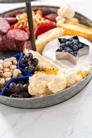 Photo for Building July 4th charcuterie board on a two-tiered serving metal stand. - Royalty Free Image