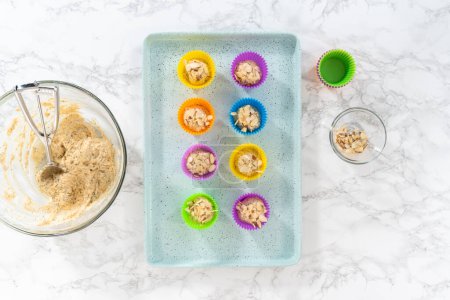 Photo for Flat lay. Scooping cupcake batter with dough scoop into silicon muffin liners to lemon poppy seed muffins. - Royalty Free Image