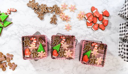 Photo for Flat lay. Packaging a homemade variety of fudge and gingerbread cookies for Christmas food gifts into tin boxes. - Royalty Free Image