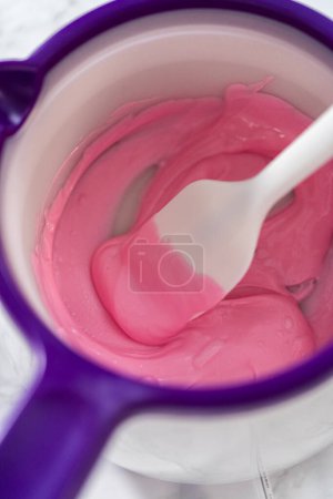 Téléchargez les photos : Fondre des pépites de chocolat rose dans un melting pot de bonbons pour faire des noeuds de chocolat pour biscuits sablés en forme de panda. - en image libre de droit