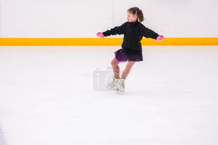 Photo for Little girl practicing before her figure skating competition at the indoor ice rink. - Royalty Free Image