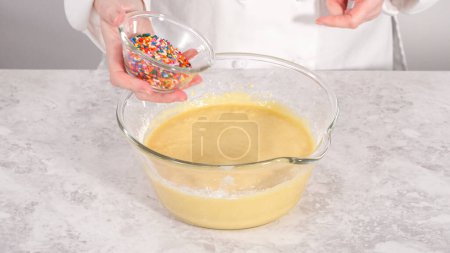 Foto de Paso a paso. Plegable en la masa de la torta arcoíris espolvorea para hornear pastel de paquete funfettti. - Imagen libre de derechos