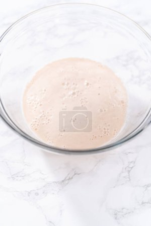 Téléchargez les photos : Activation de levure sèche dans un grand bol à mélanger en verre pour préparer la pâte à pizza. - en image libre de droit