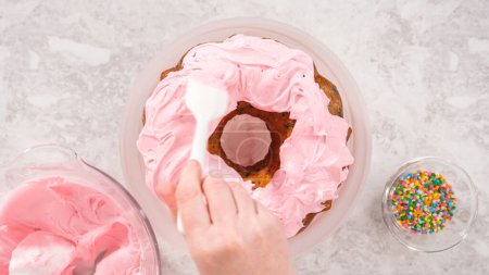 Foto de Acostado. Paso a paso. Frosting pastel de bollo funfetti con glaseado de crema de mantequilla rosa. - Imagen libre de derechos
