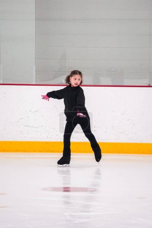 Foto de Niña practicando patinaje artístico en la pista de hielo interior. - Imagen libre de derechos