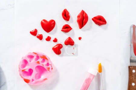 Téléchargez les photos : Dusting chocolate lips and heart-shaped chocolates with editable glitter for Valentines Day. - en image libre de droit