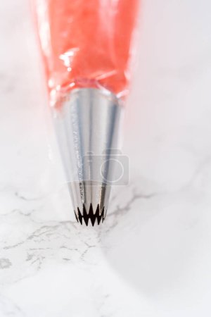 Photo for Buttercream frosting in piping bags with metal tips piping bags to decorate American flag mini cupcakes. - Royalty Free Image