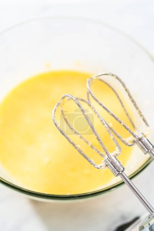 Foto de Mezclar los ingredientes en un tazón de vidrio grande para hornear pastel de terciopelo rojo con glaseado de queso crema. - Imagen libre de derechos